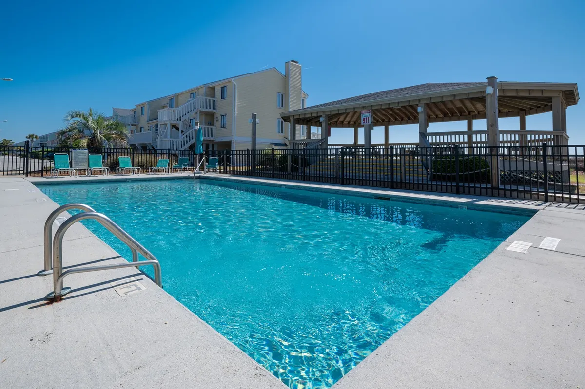 An exterior view featuring a swimming pool, gazebo, and several lounge chairs surrounded by greenery. The tranquil setting invites guests to swim, sunbathe, or socialize outdoors, reinforcing the property’s appeal for group relaxation and leisure.