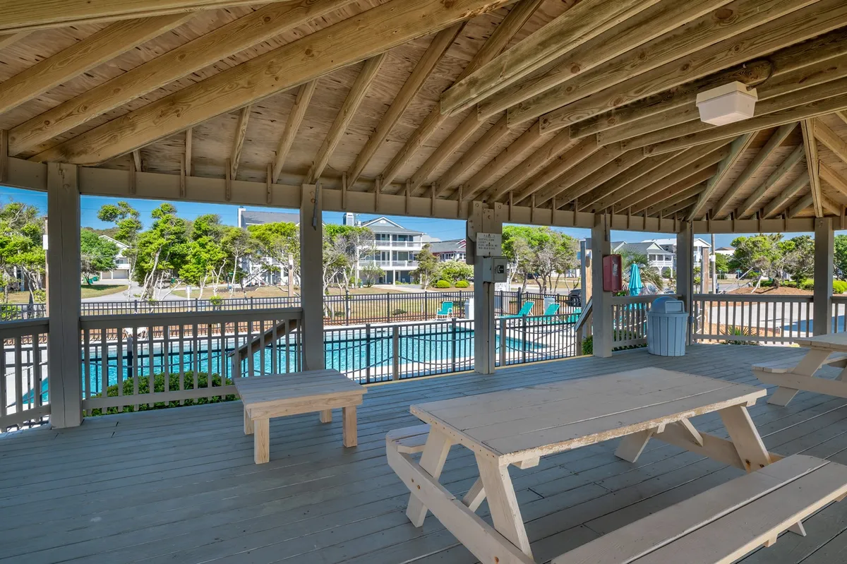 This interior image features an open structure with wooden picnic tables, a pool view, and ample natural light. It conveys a welcoming, communal space where guests can gather, dine, or relax, which complements the self-catering and convenience theme by showing areas beyond the private unit for flexible dining and relaxation.