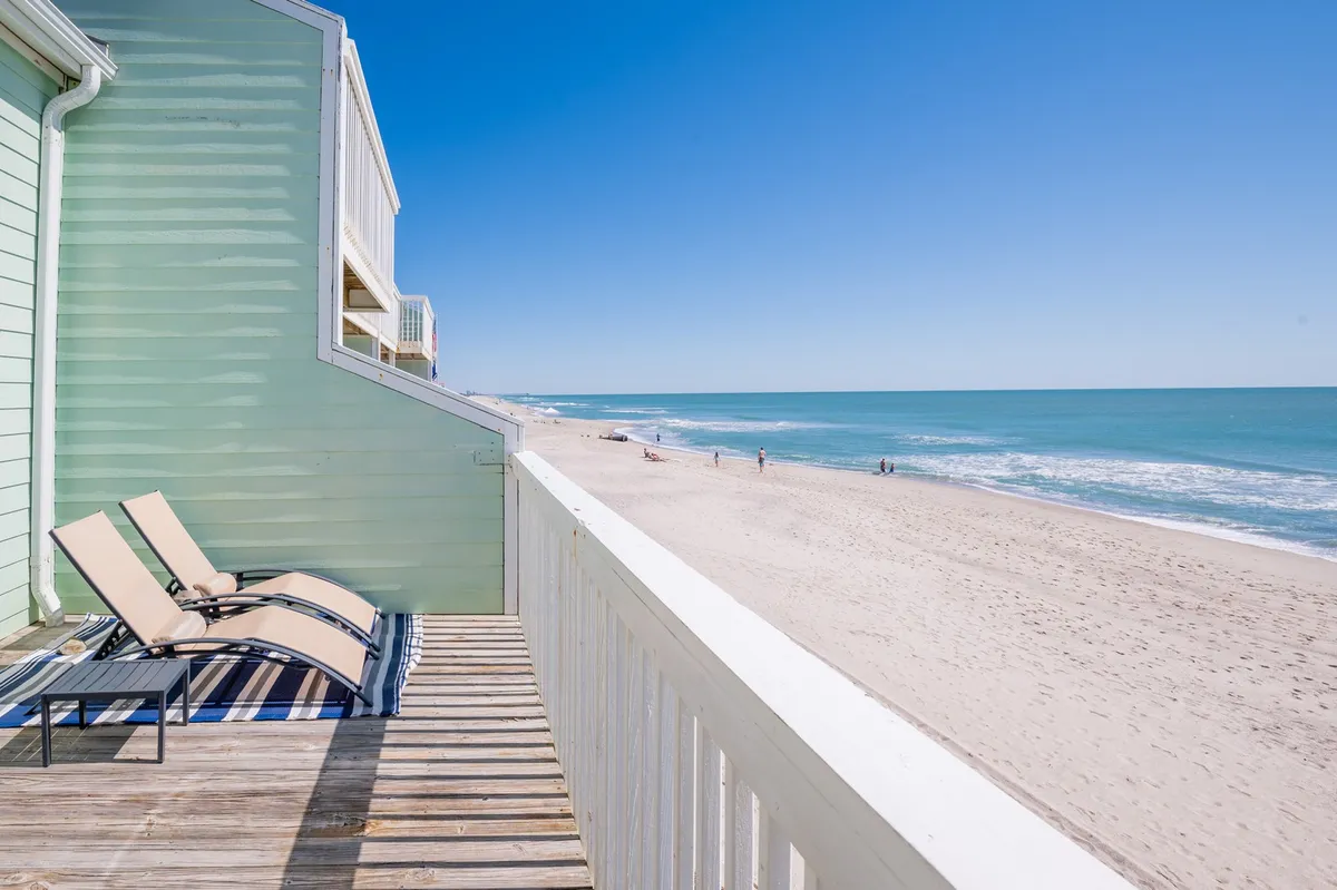 A serene exterior shot shows sun-bleached deck chairs facing the ocean, placed perfectly for sunbathing or watching the waves roll in. The soft sand and tranquil mood suggest peaceful days spent lounging by the sea, with the option for romantic sunset viewing or early morning walks.