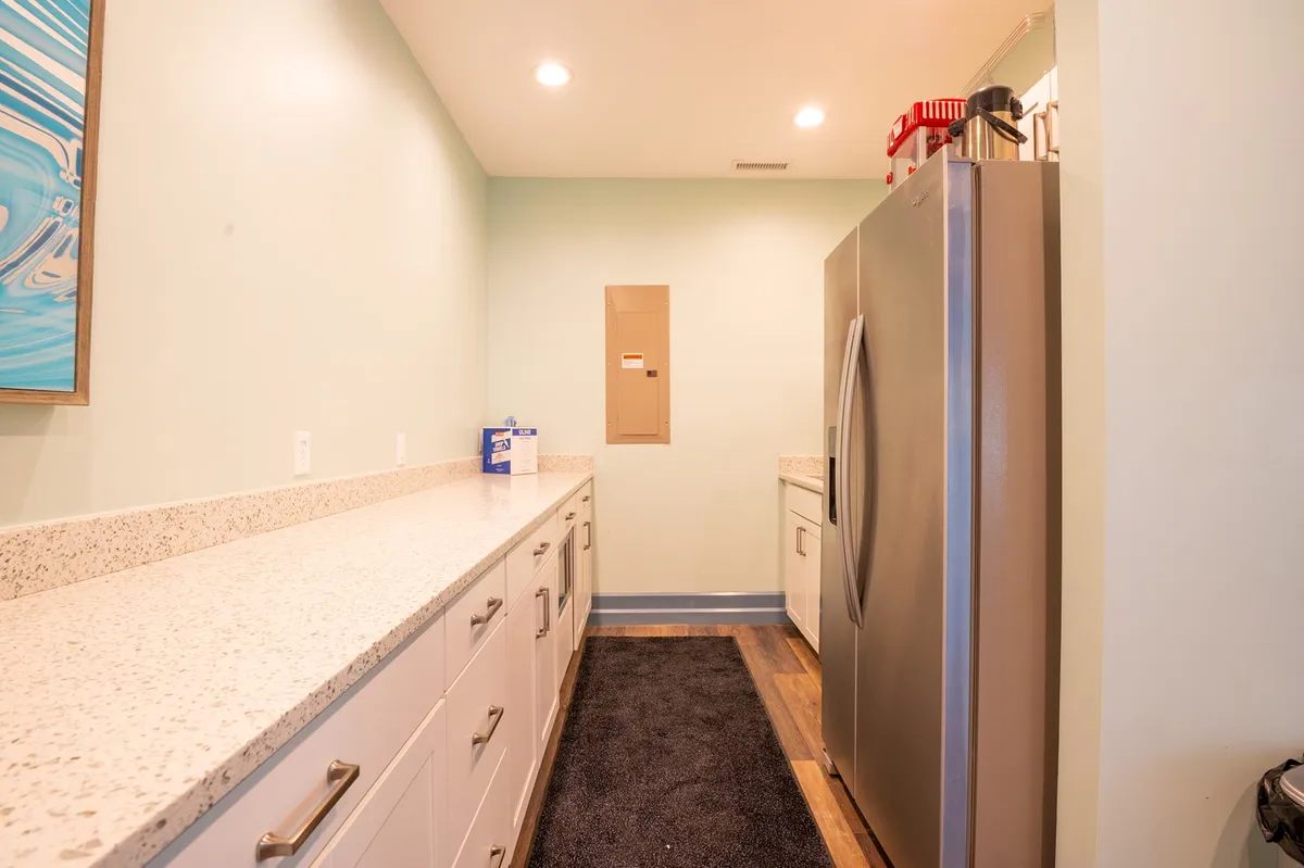 This interior shot highlights a modern, efficient kitchen space with a stainless steel refrigerator, long countertop, and ample cabinetry. The clean and organized environment nods to the self-catering aspect and the convenience of meal preparation during a stay.